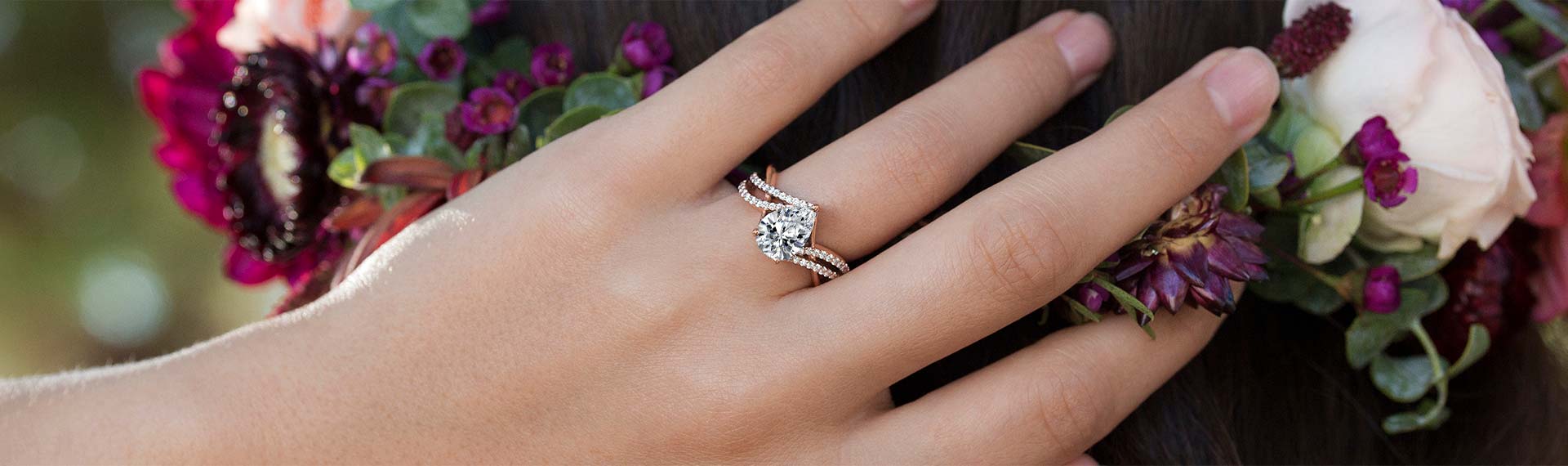 Woman wearing a diamond engagement ring with plants in the background